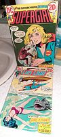 Photo showing two vintage comic books, Supergirl and Lois Lane, with clear cover artwork, titles, pricing and condition details.