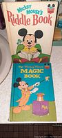 Front covers of Mickey Mouse's Riddle Book and The Mickey Mouse Magic Book showing colorful vintage artwork and titles.