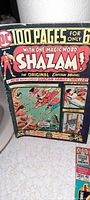 Close-up photo of the vintage Shazam 100-page comic book cover showing Captain Marvel character and storyline highlights.