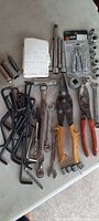 Photo showing L-shaped Allen wrenches, cutters with yellow and red handles, combination wrenches, and loose sockets with extension bars.