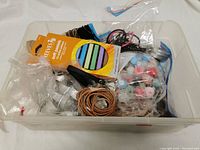 Photo showing a plastic bin with assorted crafting supplies including Fimo clay, beads, leather straps, and plastic containers.