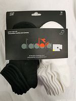 Front view of unopened package containing 10 pairs of Diadora junior's low cut everyday training socks in black and white colors, size small.