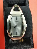 Front view of the silver Guess wristwatch showing rectangular silver dial with GUESS logo and simple black hour markers and hands.