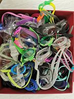 Top view of large box filled with assorted swimming goggles in various colors and styles