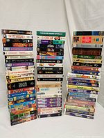 Photo showing three large stacks of VHS tapes, highlighting the variety of titles including Disney movies, Robotech anime, and other classic films and documentaries.