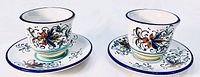 Set of two ceramic cups with matching saucers, front view showing floral pattern on cups and saucers.
