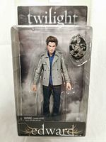 Front view of the Edward doll action figure in original unopened packaging with Twilight branding, showing the doll dressed in jacket, shirt, and pants with accessory badge.