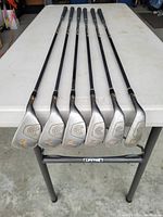 Full view of the six Cleveland HiBore irons showing club heads with numbers 3 to 8 and Cleveland logo