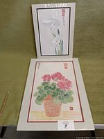 Two Oriental brush paintings, one with pink flowers in a pot (16" x 22") and one with white calla lilies (12" x 16"), both wrapped in cellophane.
