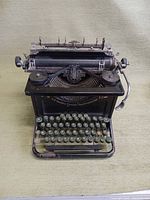 Front view showing the keyboard, type bars, ribbon spools, and carriage return lever, with wear and paint chipping visible.