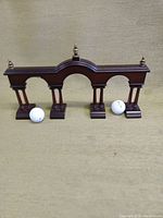Front view of wooden archway golf putting aid with two golf balls adjacent