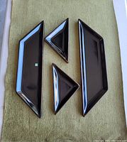 Four black ceramic sushi platters on green cloth: two long rectangle platters and two smaller triangles.