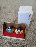 Two Japanese porcelain trinket figurines displayed in a branded box with Japanese characters on the box lid.