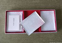 Three rectangular porcelain trays with a textured white and light pattern, sitting inside a red-lined gift box with a paper insert included.