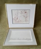Two framed charcoal studies: one showing a figurative drawing and the other an abstract or minimalistic drawing. Both works are mounted under matt and glass in anodized aluminum frames.