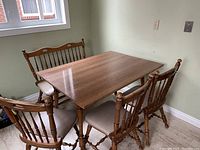 Wide view of kitchen table with chairs and bench against wall, natural light from window.