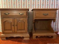 Both Roxton bedside tables side by side against floral wallpaper on carpet, showing overall design, finish, and hardware.