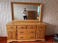 Front view of the full wooden dresser with attached mirror reflecting the room and person taking photo.