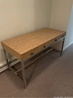 Full view of the wood top desk with metal legs against wall.