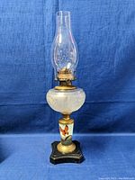 Full view of the 20-inch tall antique kerosene lamp showing the glass chimney, etched glass font, hand-painted ceramic section, brass fitting, and black wooden base.