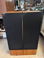 Front view of both KEF C80 speakers with black grill covers and wood veneer cabinet.