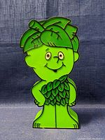 Front view of Little Sprout shaped radio showing facial features, leaf hair and attire details in bright green plastic with darker green lines.