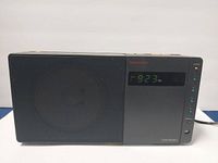 Front view of Nakamichi Clock Radio showing speaker grill and digital clock display with AM/FM indicators and memory buttons.