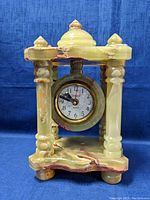 Front view of onyx clock with visible dial and carved columns and domed top.