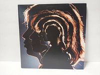 Front side of the album cover featuring silhouettes of The Rolling Stones band members in profile with an orange-brown glow on black background.