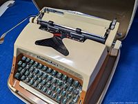 Front angled view of vintage beige and brown Commodore typewriter with green keys.