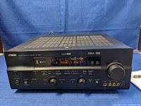 Front view of Yamaha AV receiver showing main controls, display, volume knob, and input ports.