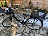 Side view of black Globe-Carmel step-through frame bicycle with front wire basket, rear wire basket, black saddle and kickstand