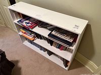 Front view of white wood bookshelf filled with books and other items.
