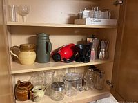 Shelf with assorted coffee makers, ceramic jugs, glass containers and pitchers