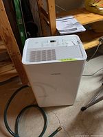 Front and top view of white rectangular Noma dehumidifier with vent grills and digital control panel.