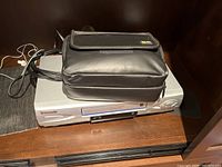 Silver Panasonic 4 Head Hi-Fi Stereo VHS Player with black carrying case on top.