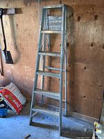 Full view of the aluminum folding ladder showing six steps with some paint and wear marks.