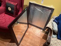 Two matching square mirrors with dark wood frames leaning against wall and chair, showing overall size and condition.