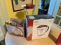 Photo of Hamilton Beach MixMate Ultra hand mixer box, Master Chef water filter pitcher box, and Hamilton Beach Wave Action blender jar base and lid on table.