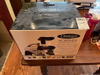 Photo of the boxed Omega NC800HDS juicer from the front, showing branding and model.