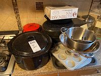 Black enamel roasting pans with lids, fluted cake pan box, stainless steel mixing bowls, baking pans including muffin tins