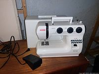 Front view of Janome portable sewing machine model SUV1122 with foot pedal and power cord