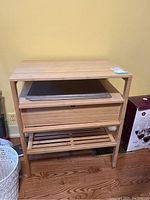 Front view of the wooden shelving showing the upper shelf, middle drawer and lower slatted shelf.