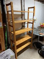 View of the wooden shelving unit showing five shelves and adjustable side panels.