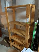 Full view of wooden shelving unit with five shelves in basement setting showing natural wood finish and construction.
