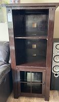 Front view of one dark wood painted display cabinet showing two interior adjustable shelves and a lower door with no glass.