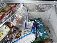 Interior view showing frosted compartment and frozen contents inside the freezer.