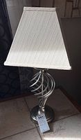 Full view of one lamp showing the fabric shade and spiral brushed nickel base