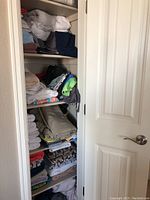 Closet with multiple shelves holding folded bath towels, bed linens, and window coverings in different colors and patterns