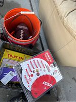 Photo showing halo orange bucket with Craftsman tools and football inside, crate with vintage Smart-A game box next to it, Diablo saw blades package on top